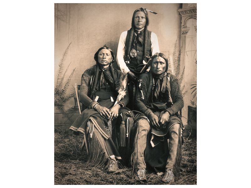 (Left to right) Chief Quanah Parker with Quas-si-yah and Frank Moeta, circa 1890. Taken at the Red Store.