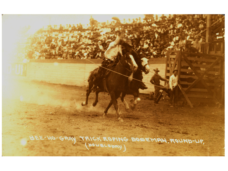 Bee Ho spinning a rope around himself and another rider, Boseman Roundup, circa 1914.